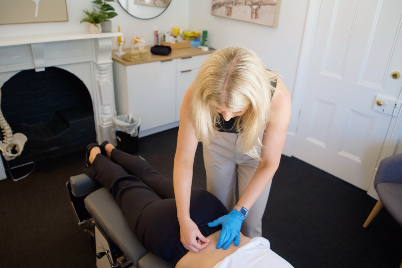 A chiropractor doing dry needling on a prone patient