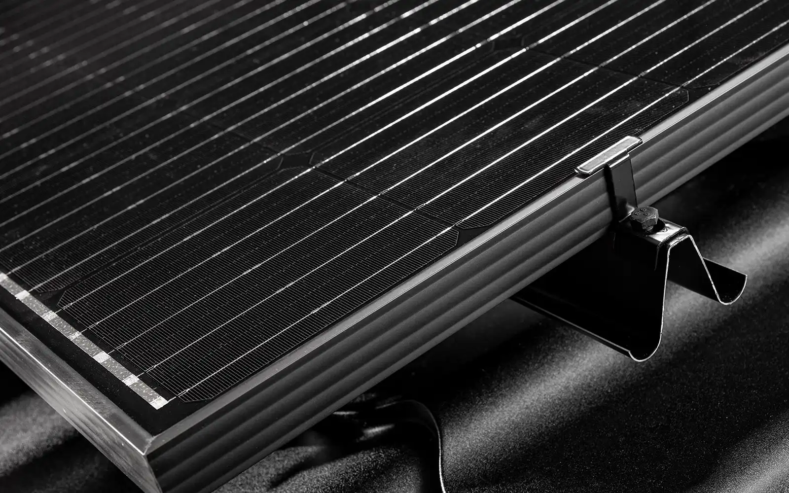 Lähikuva mustasta aurinkopaneelista kiinnitettynä metalliseen Rauli kattokannattimeen.