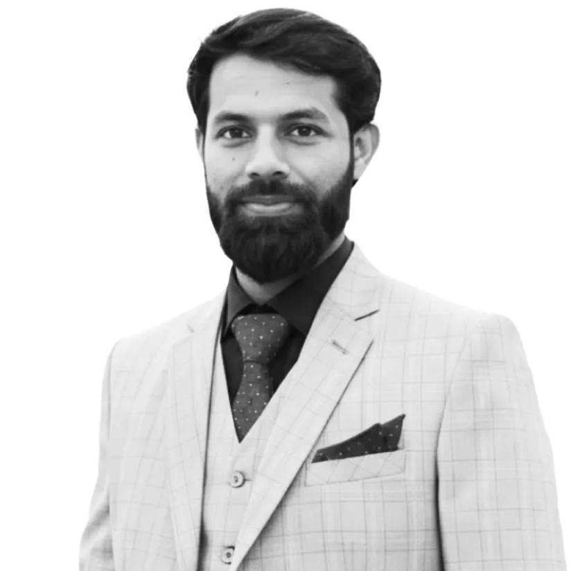 Portrait of a man with a beard wearing a light checkered suit, dark shirt, and polka dot tie.