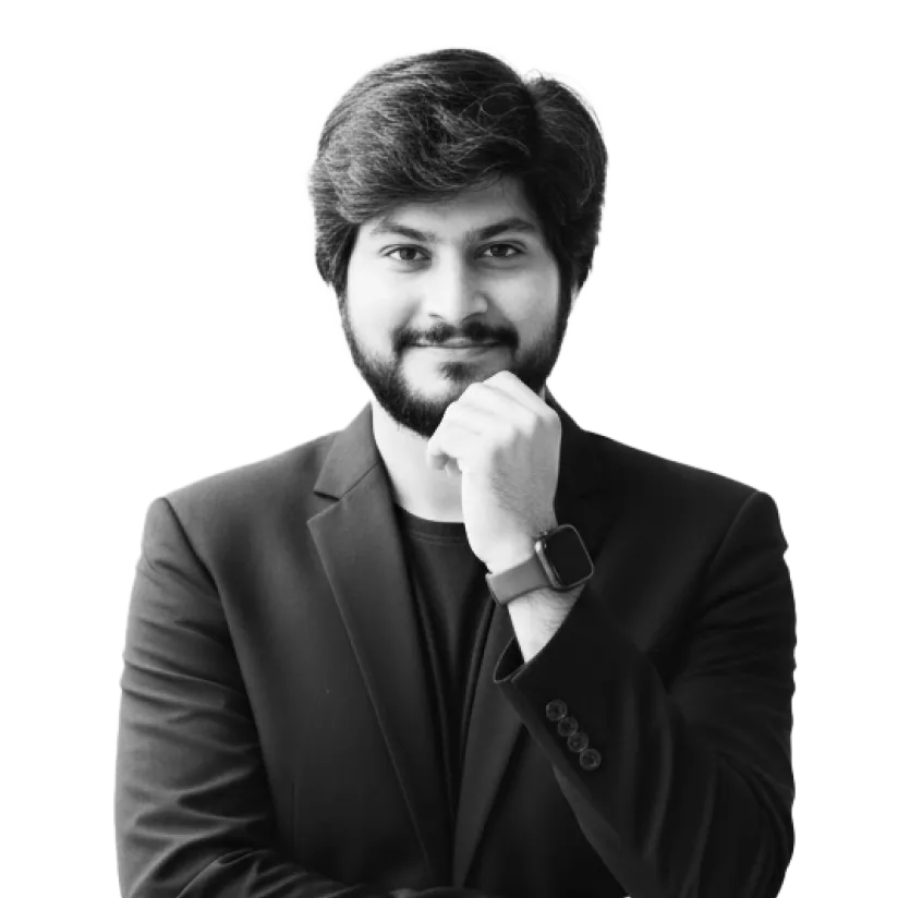 Smiling man with beard and dark hair wearing a black blazer and smartwatch, resting his chin on his hand.