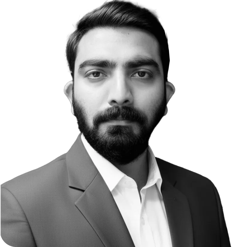 Black and white portrait of a serious bearded man wearing a suit jacket and white shirt against a black background.
