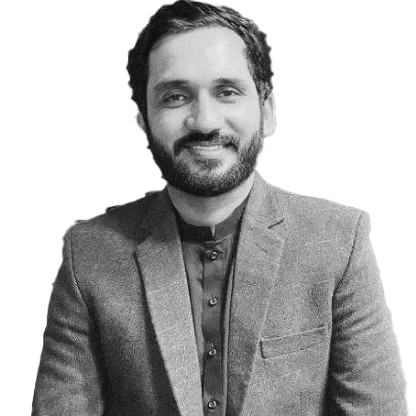 Smiling man with beard wearing a buttoned-up blazer and traditional shirt.