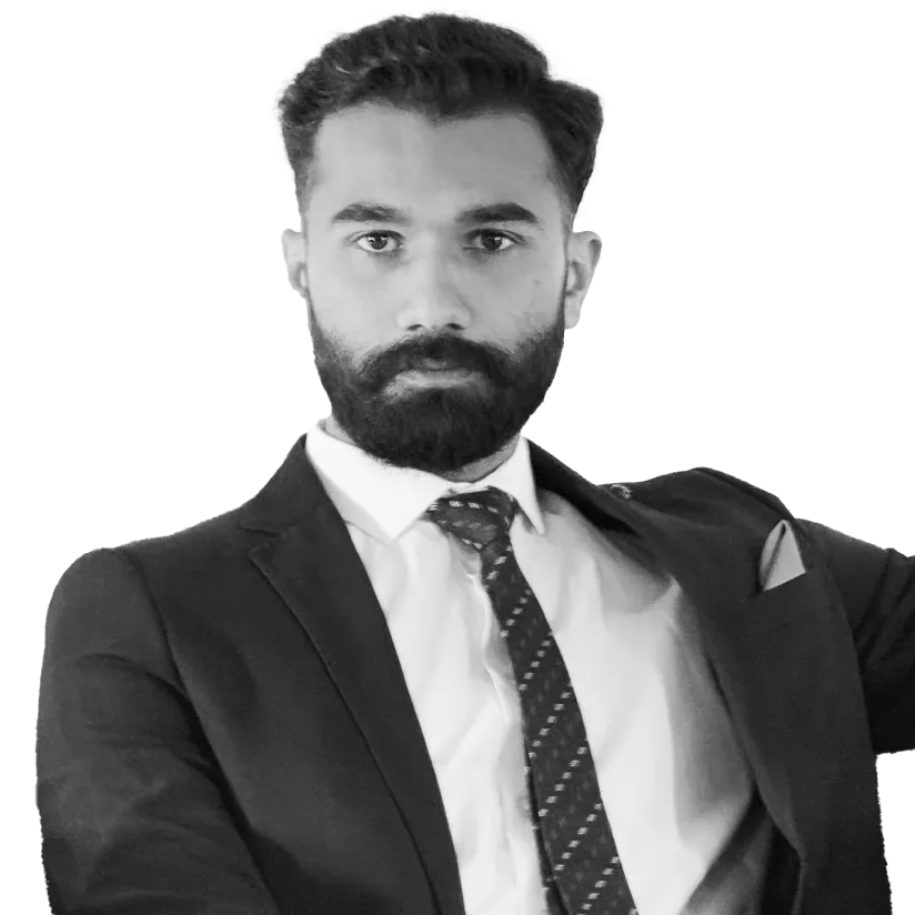 Man with a beard wearing a dark suit, white shirt, and patterned tie looking directly at the camera.