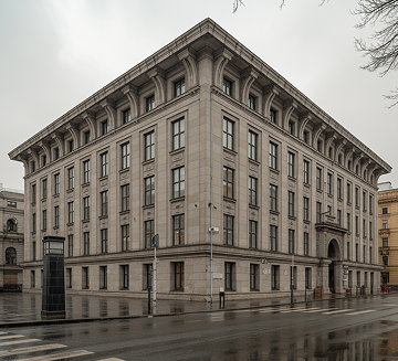 Large gray stone building with classical architectural details on a rainy street corner.