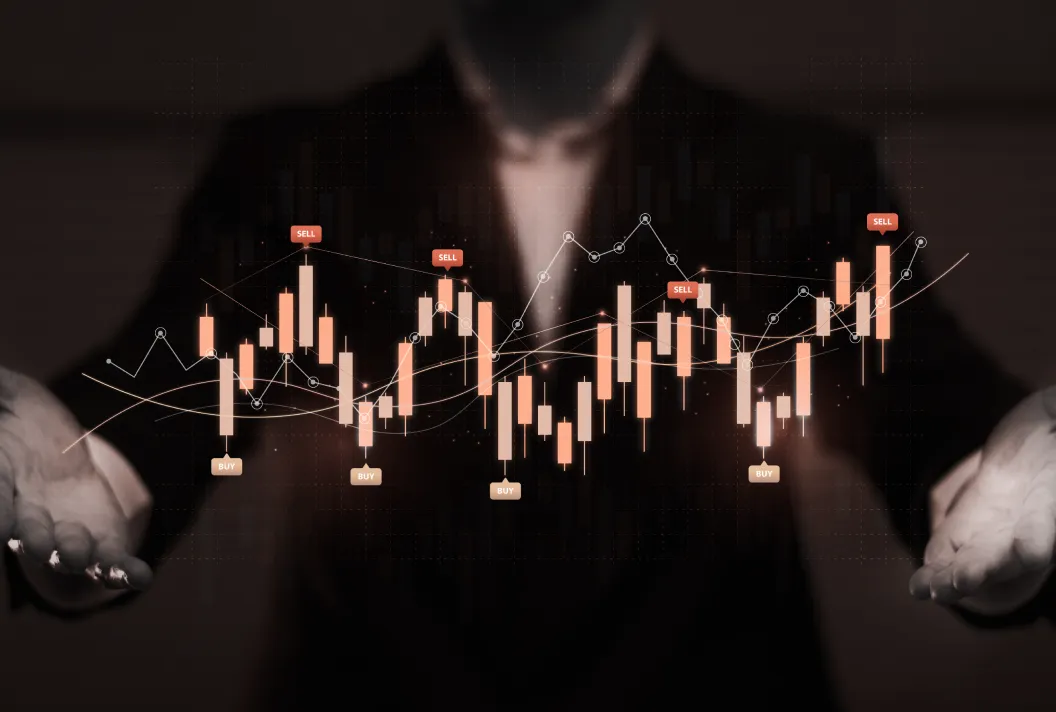 Person in dark suit holding a holographic stock market candlestick chart with buy and sell indicators.
