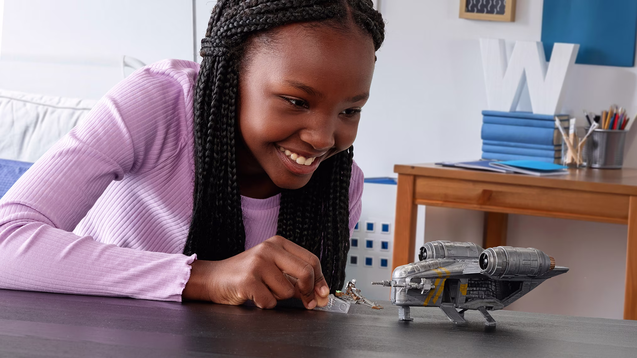 Girl playing with a Star Wars toy spacecraft and miniature figures on a table