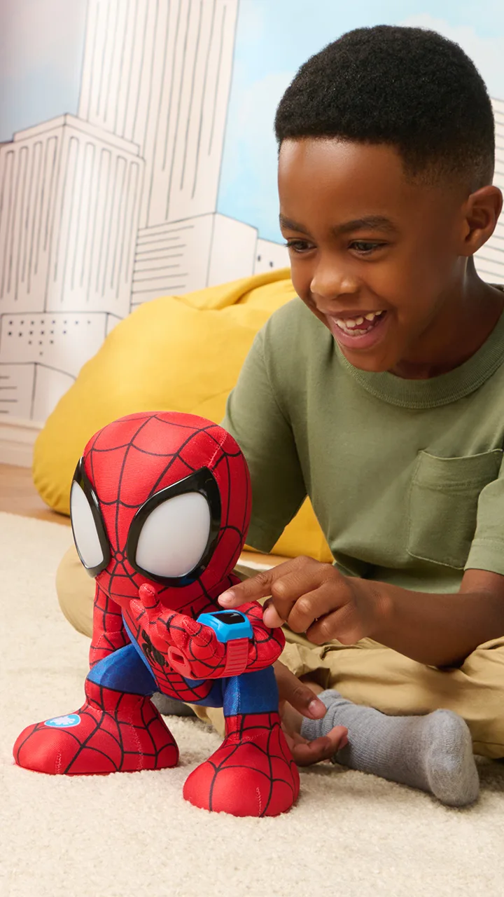Close-up of child pressing the spider emblem on a Spidey plush toy