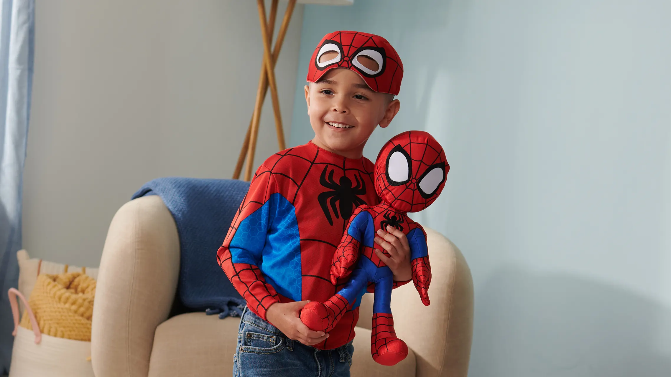 Boy dressed as Spider-Man holding a Spidey plush toy
