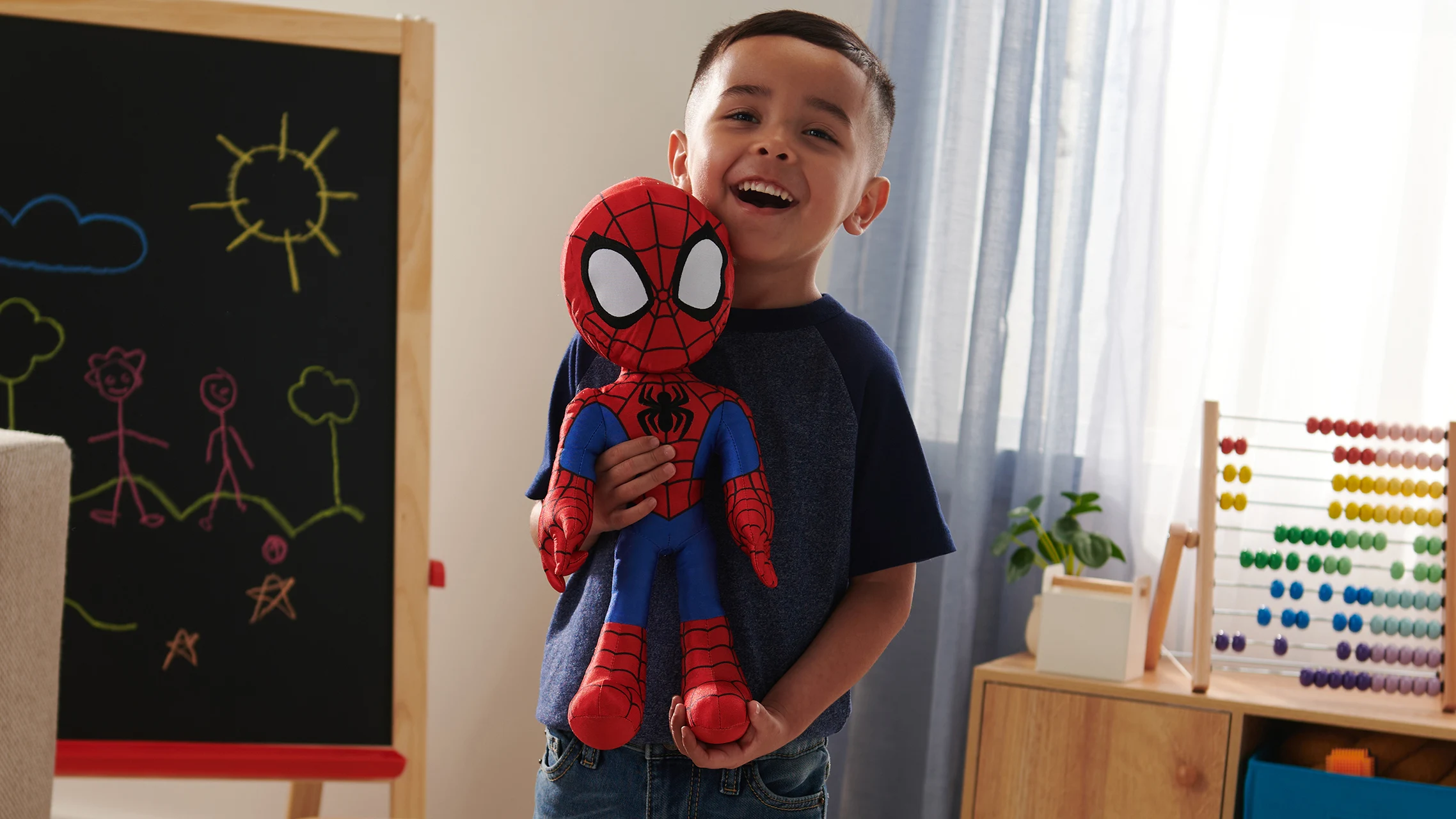 Child holding a Spidey plush toy from Marvel Spidey and His Amazing Friends