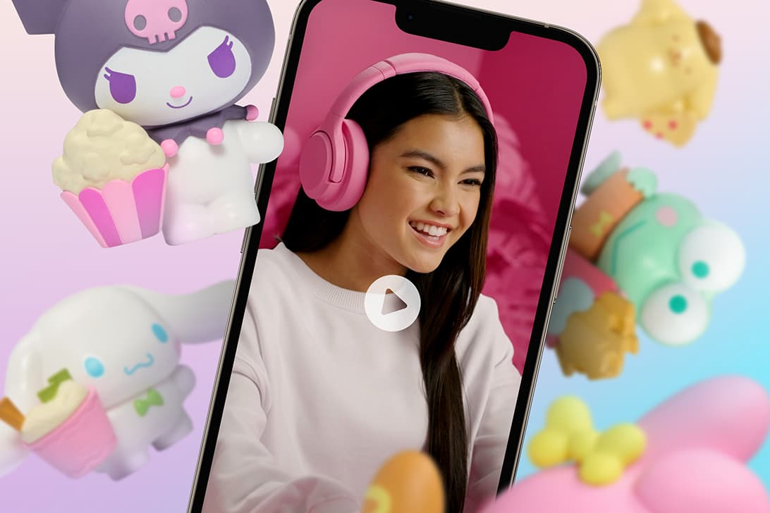 Smartphone displaying a video call with a girl wearing pink headphones surrounded by Hello Kitty characters and colorful toys