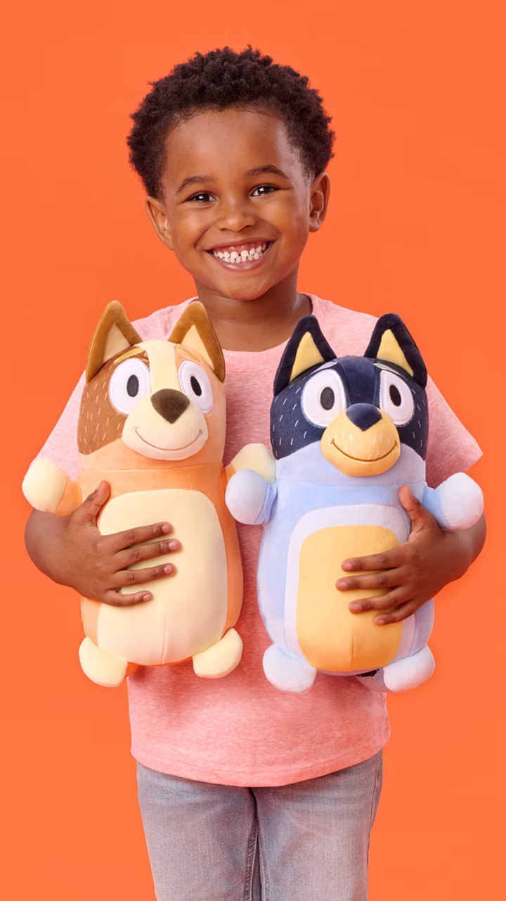 Child smiling while holding a HugMees Squishmallows plush toy