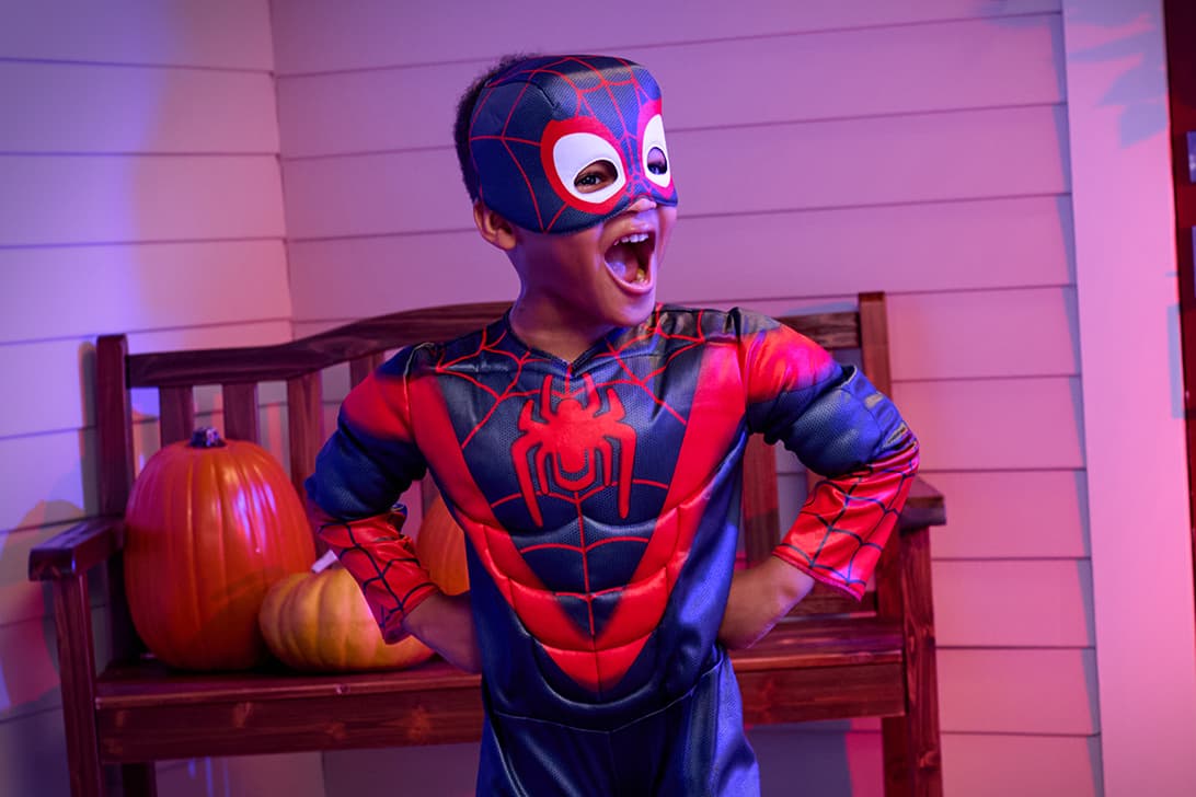 Child wearing a Spider-Man costume standing in a playful hero pose