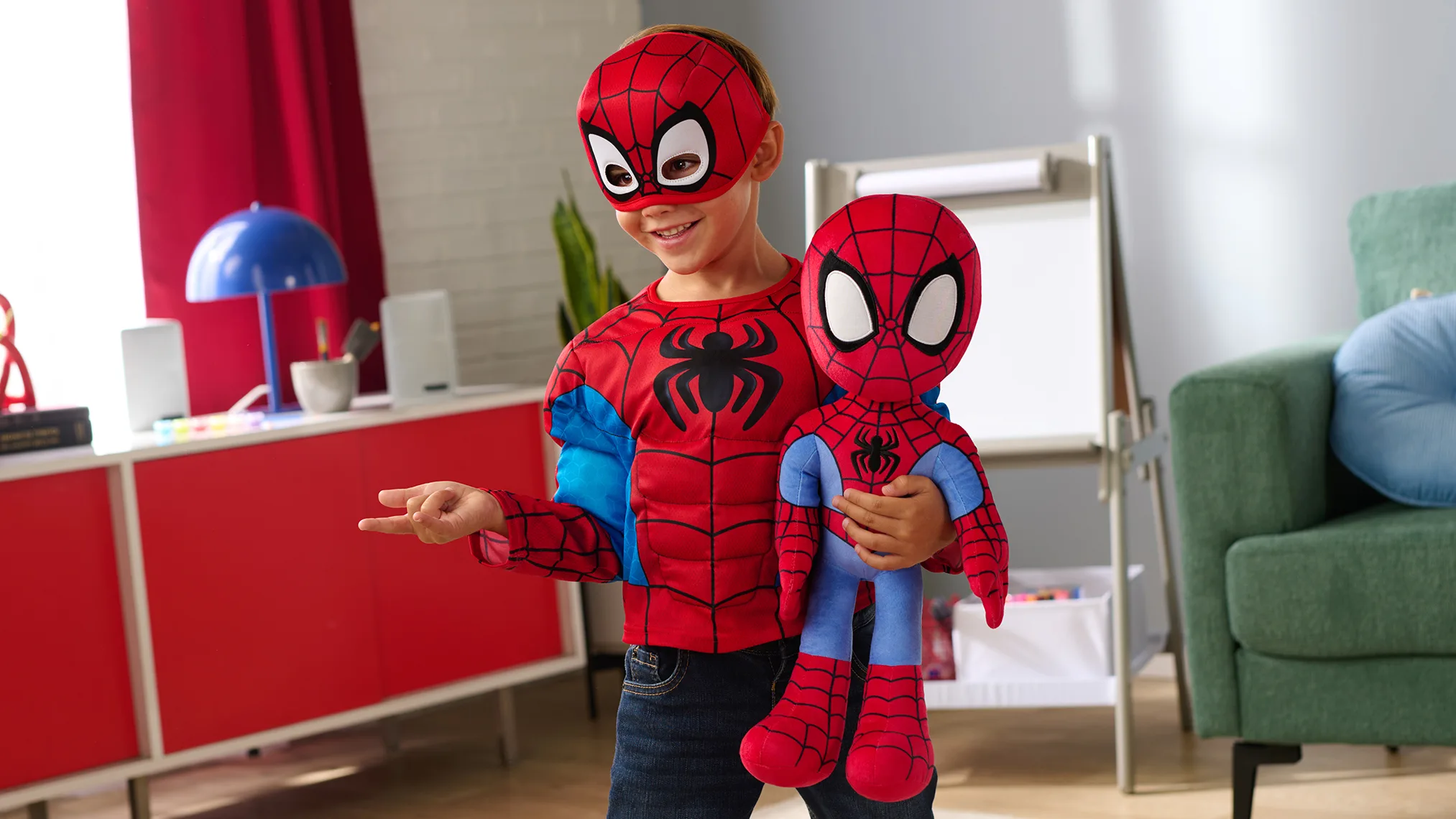 Child holding a Spider-Man plush toy while wearing a Spider-Man costume