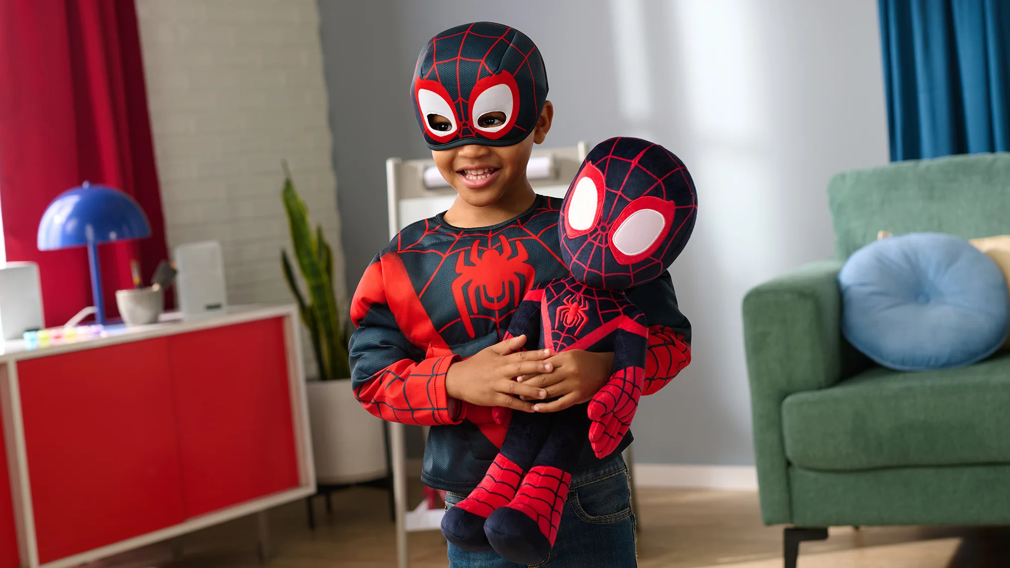 Child holding a Spider-Man plush toy while wearing a Spider-Man costume