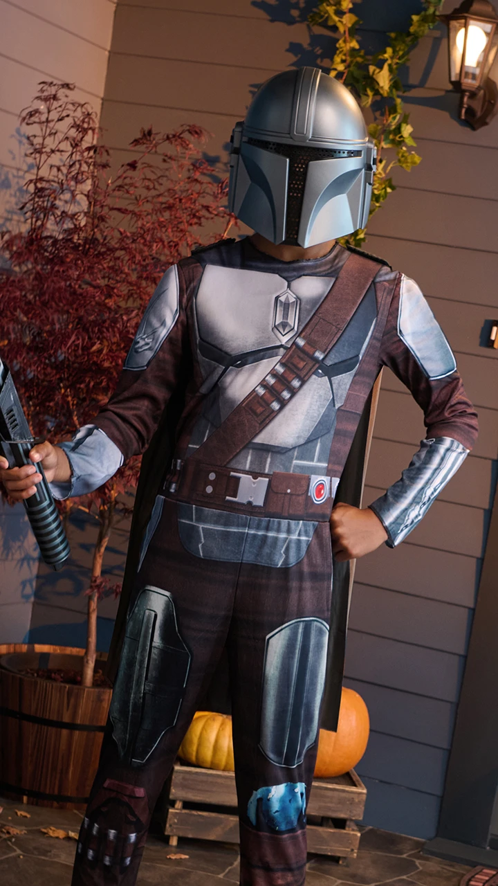 Child wearing a Mandalorian costume holding a toy lightsaber