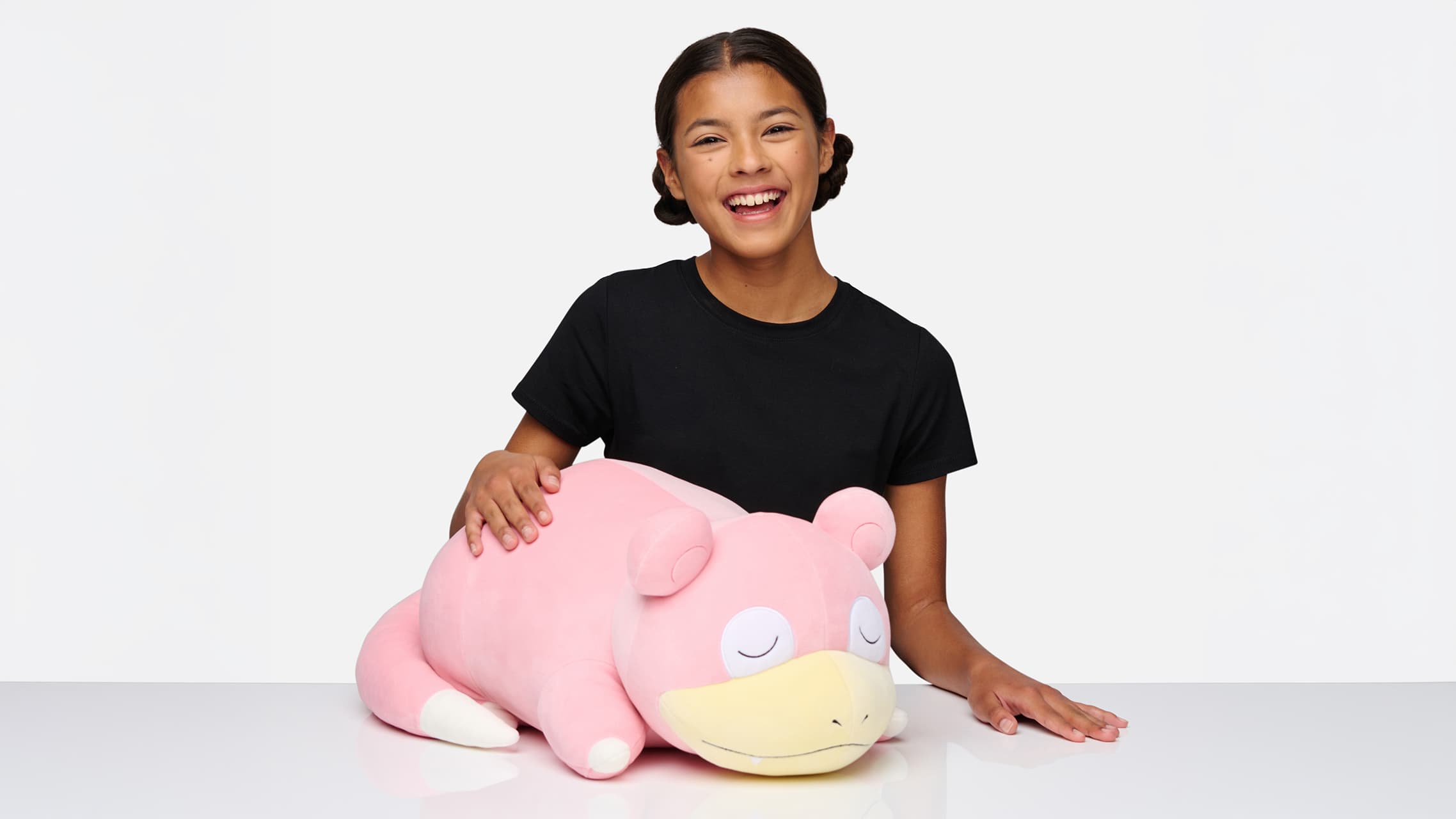 Child with Slowpoke Pokémon plush toy on white studio background