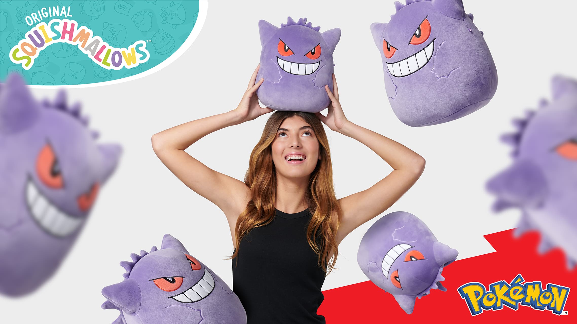 Woman balancing a Gengar Squishmallows plush on her head with floating plush toys