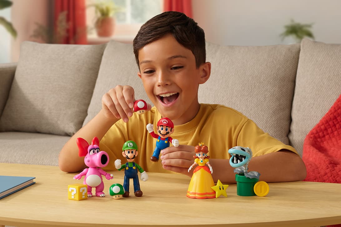 Child playing with Super Mario character figures including Mario, Luigi, and Princess Daisy