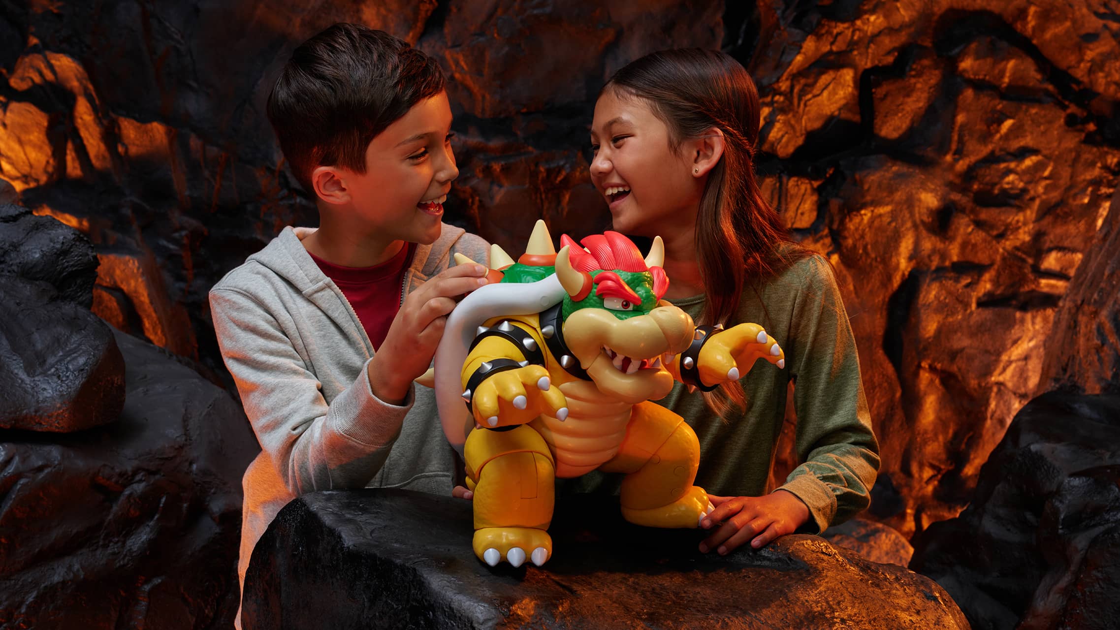 Two kids playing with Bowser toy figure from Super Mario