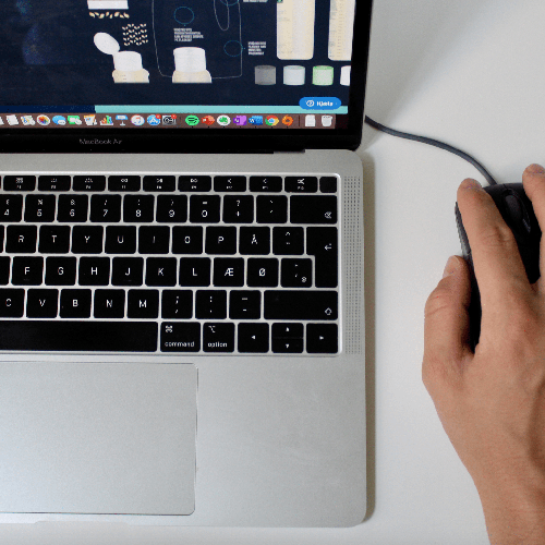 Hånd der bruger en kablet mus ved siden af et MacBook Air tastatur med skærm, der viser forskellige kosmetikprodukter.