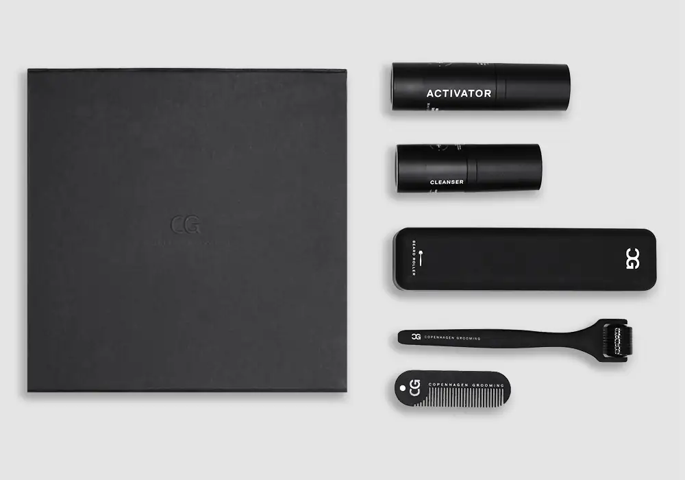 Sort plejesæt med aktiveringsspray, rensemiddel, skægroller, en kam og en æske.