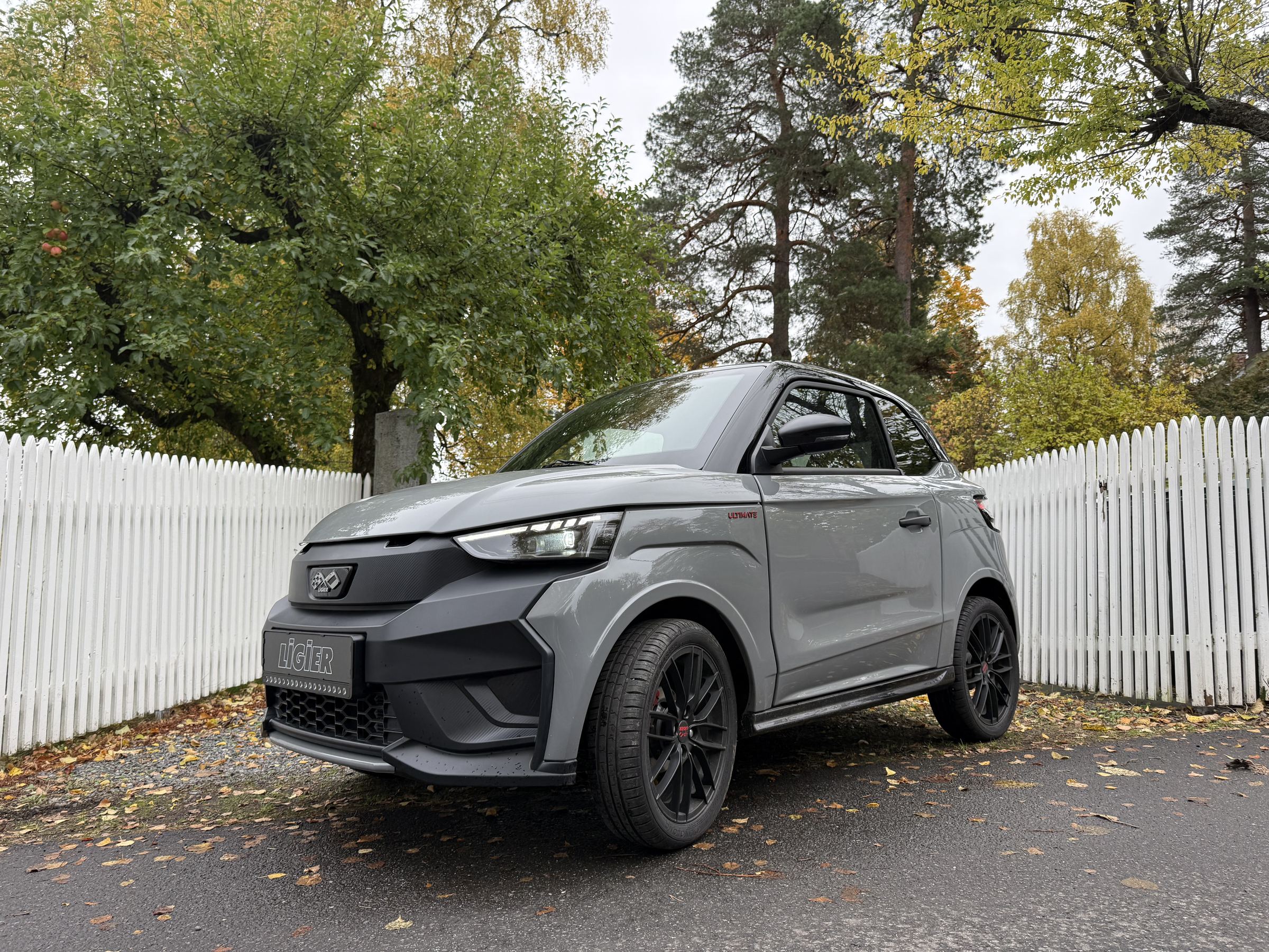 Grå Ligier JS50 EV foran et hvitt stakittgjerde