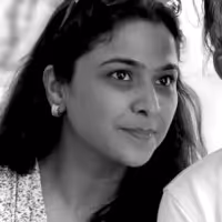 Woman with long dark hair and earrings, looking attentively.