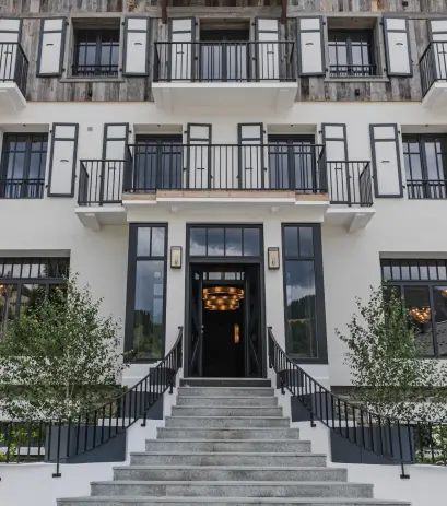Entrée principale de l'Écrin de Megève avec des balustrades noires et plusieurs balcons au-dessus.