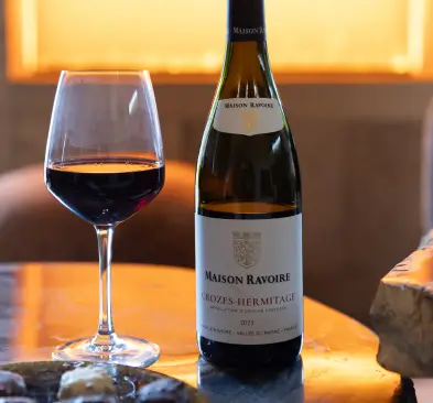 Bouteille de vin avec un verre de vin rouge sur une table en bois.