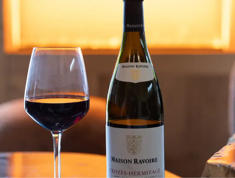 Bouteille de vin avec un verre de vin rouge sur une table en bois.