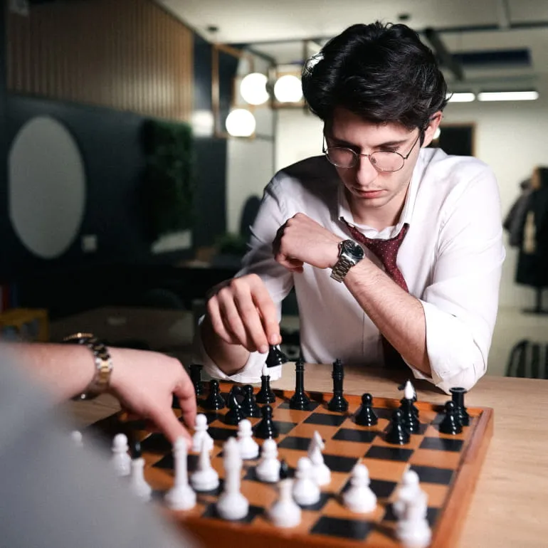 Two people sitting and discussing indoors with a laptop on a glass table.