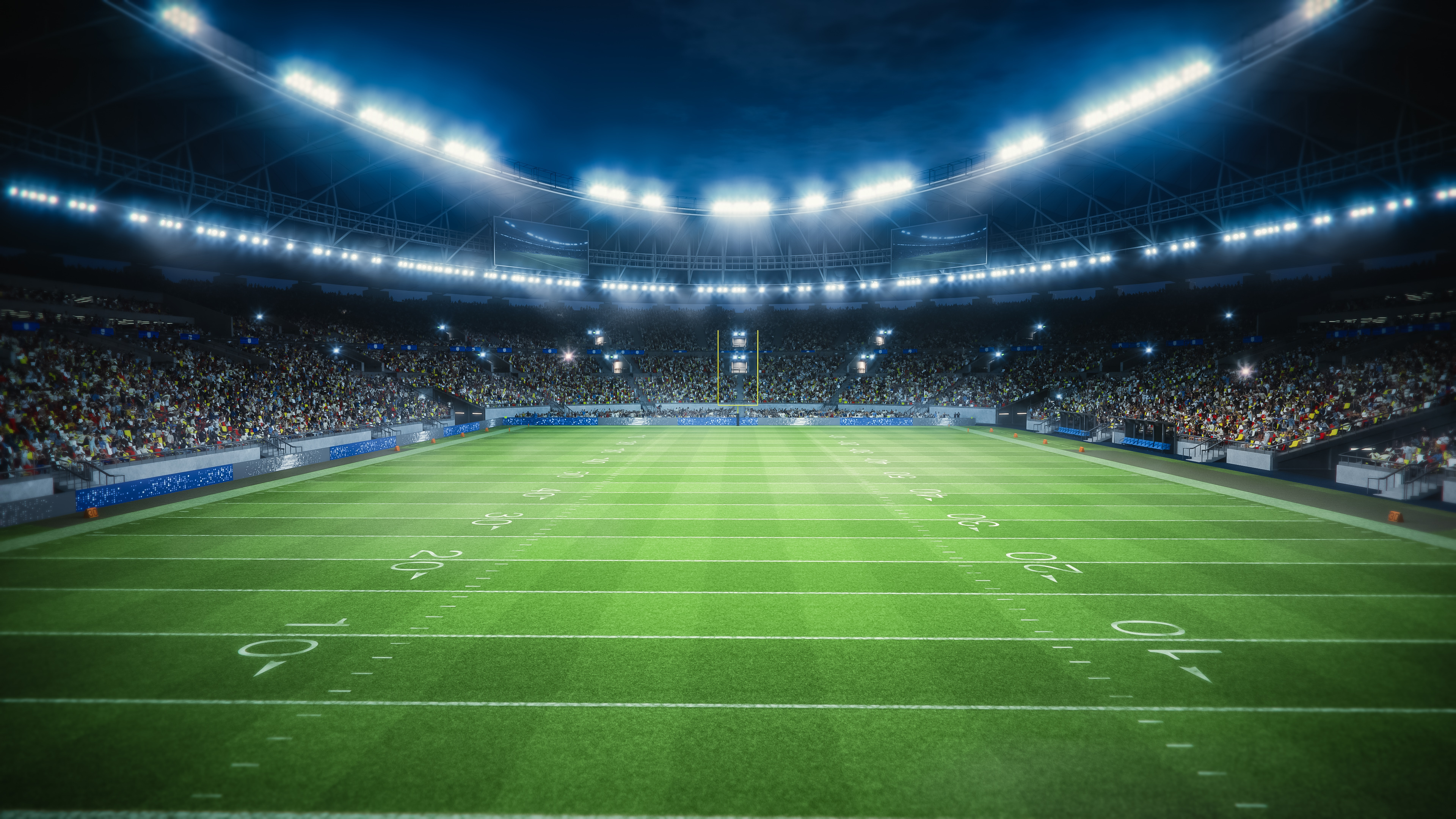 Football field with flashing lights and large crowd. 