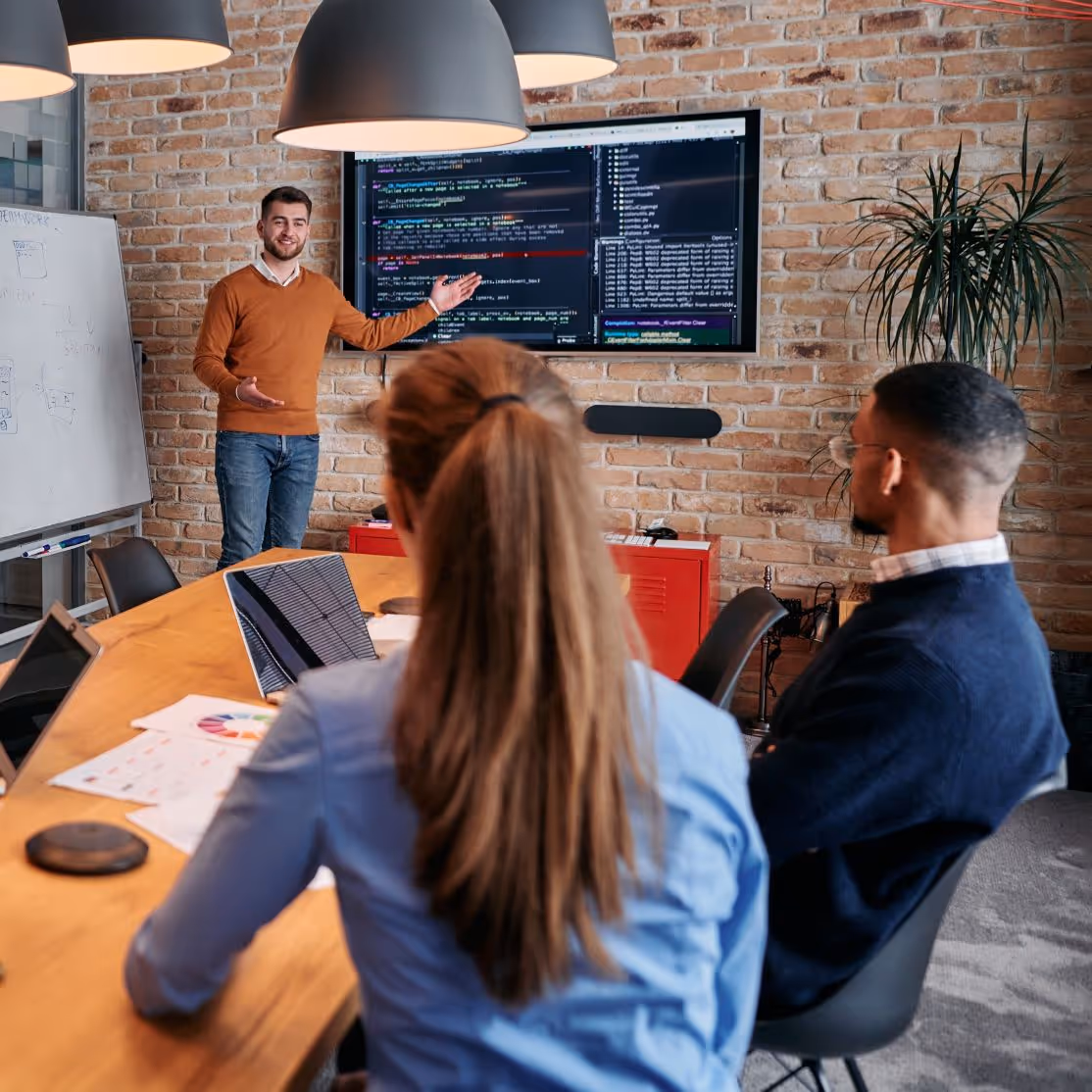 A man is presenting to two colleagues in a meeting room