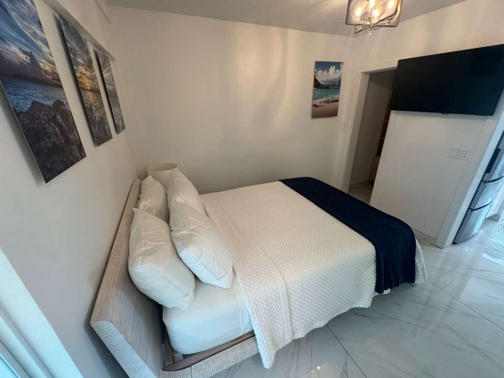 Bright bedroom with white bedding and navy throw in DGMI Properties luxury suite Cruz Bay St. John.