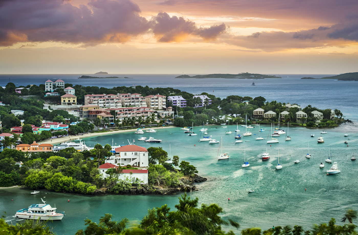 Sunset view over Cruz Bay harbor St. John US Virgin Islands with boats and DGMI Properties luxury apartments.