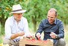 Piers from Little Freddie, and a farmer sitting outdoors, sorting through fresh produce.