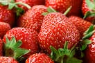 Close-up of fresh ripe red strawberries with green leaves.