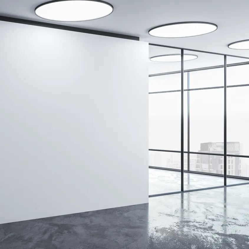 Modern office interior with large windows, a polished concrete floor, and circular overhead lights.