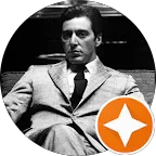 Black and white portrait of Al Pacino as Michael Corleone from "The Godfather," wearing a suit and tie, with a serious expression. The image is framed with a circular border, and features an orange star icon at the bottom right.
