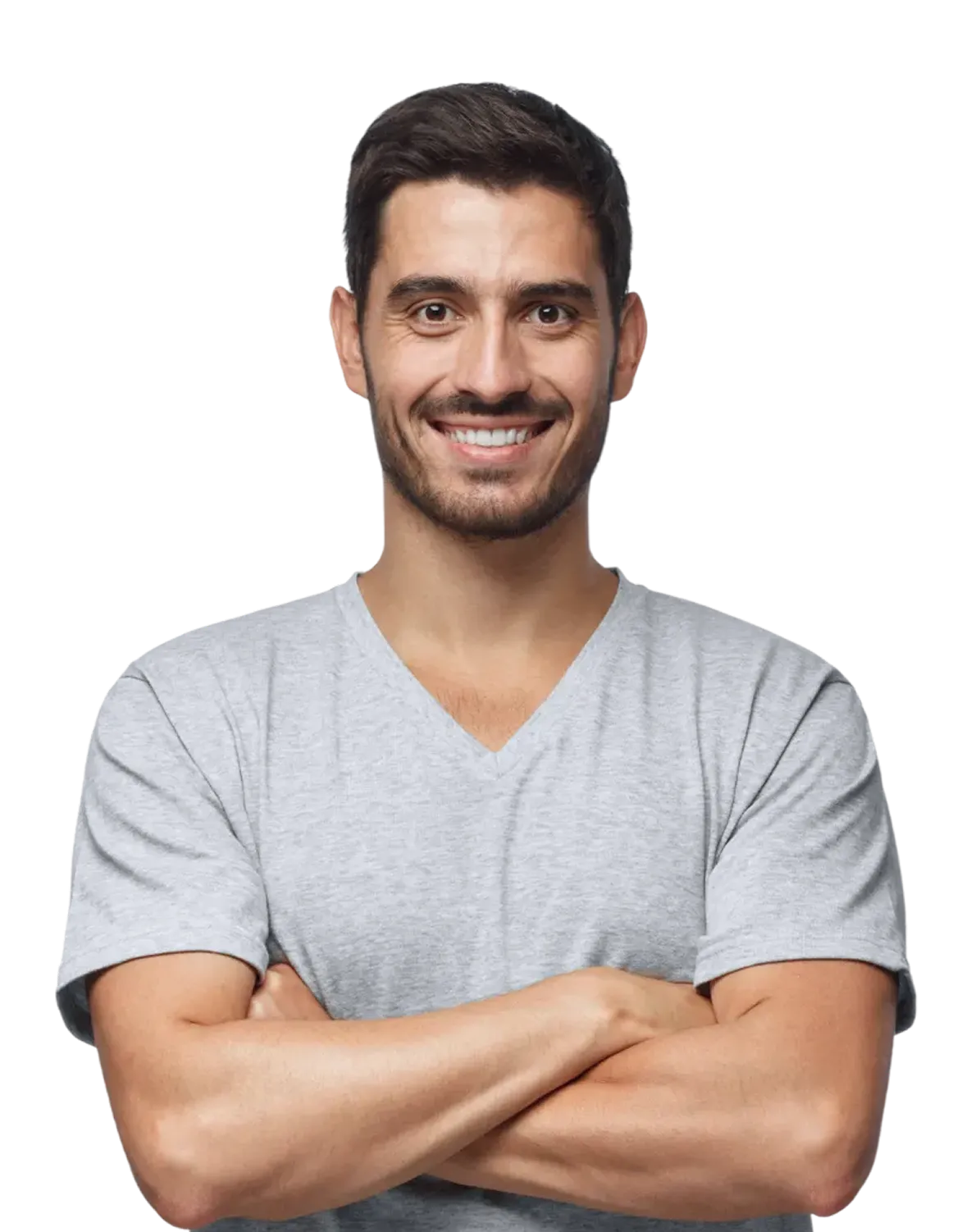 A man with short dark hair and a beard, wearing a light gray V-neck T-shirt, smiles and crosses his arms in front of him.