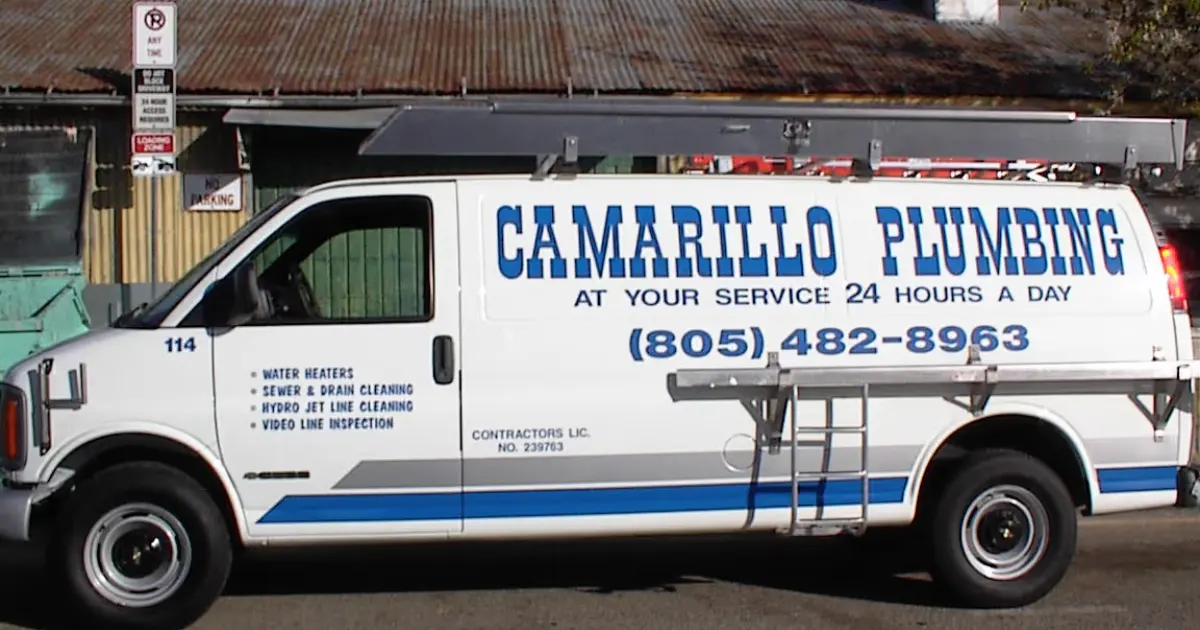 White plumbing service van with blue text reading 'Camarillo Plumbing, At Your Service 24 Hours a Day' and phone number (805) 482-8963 parked on street.
