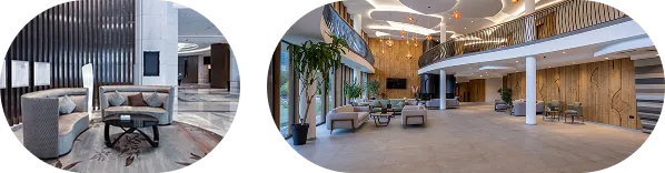 Spacious modern hotel lobby with beige seating, large windows, plants, and wooden decorative panels.