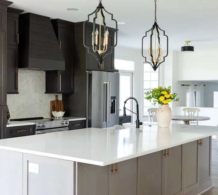 Sleek kitchen remodel with black cabinetry, brass hardware, and white quartz island.