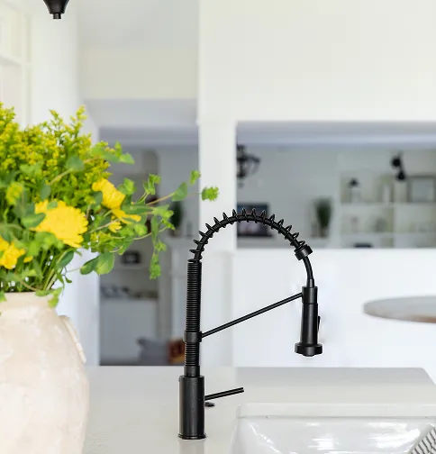 Matte black pull-down kitchen faucet on a bright island installed during a kitchen renovation.