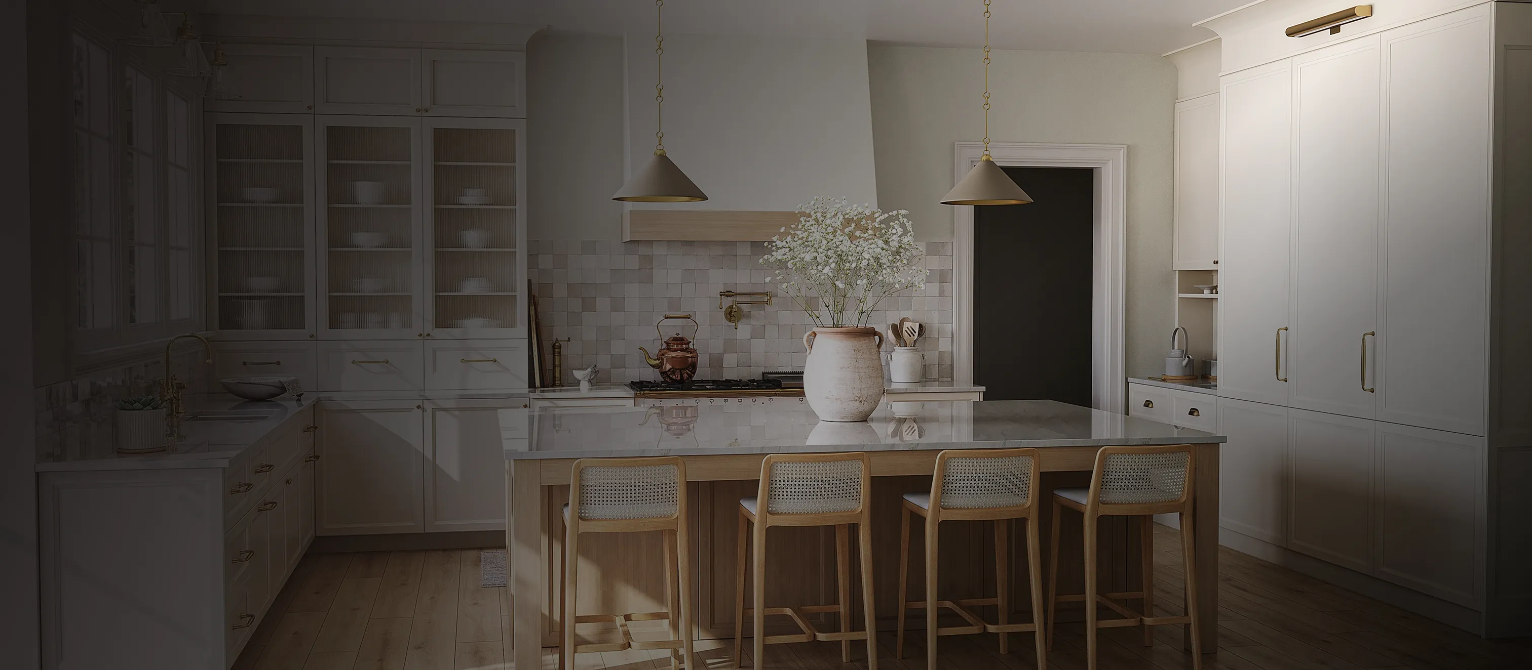 Elegant white kitchen with a large island, brass accents, and soft pendant lighting.