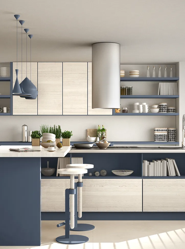 Modern kitchen with blue and light wood cabinets, white countertop, two bar stools, hanging blue pendant lights, and open shelves with dishes and plants.