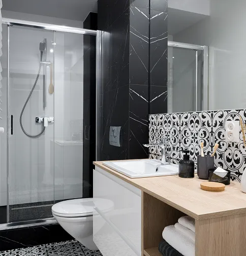 Contemporary bathroom remodel with glass shower, wood vanity, and bold patterned tile.