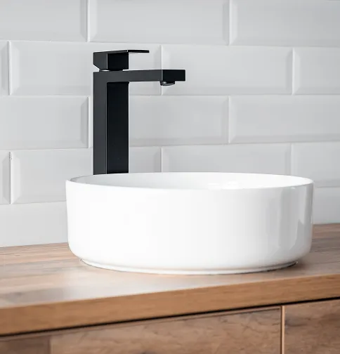 White vessel sink with matte black faucet on wood vanity in an updated bathroom.
