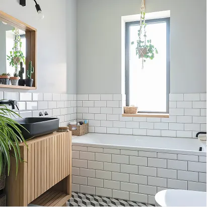 Bright bathroom featuring subway tile, wood vanity, and hanging plants after renovation.