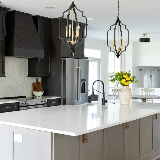 Sleek kitchen remodel with black cabinetry, brass hardware, and white quartz island.